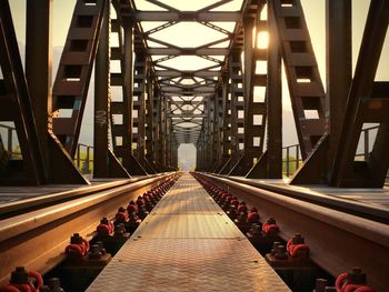 Diminishing perspective of railway bridge against sky during sunset