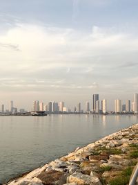 Sea by city buildings against sky