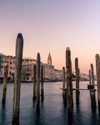 View of wooden posts in river against buildings