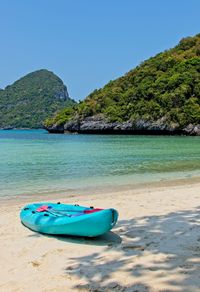 Boat moored on beach against clear blue sky