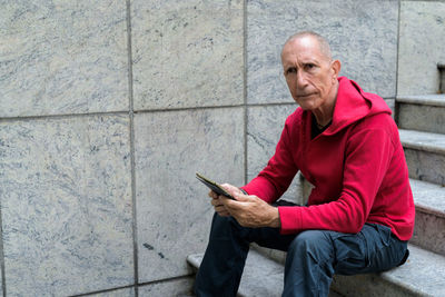 Portrait of man using mobile phone while sitting outdoors