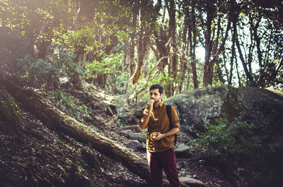 Man eating while standing in forest