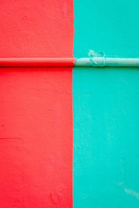 Close up of red and green colored wall with pipe in burano