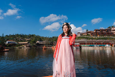 Portrait of young woman standing against lake