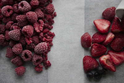 Piles of raspberries and strawberries on table