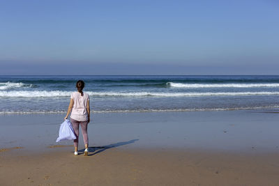 Rear view of woman on beach against sky