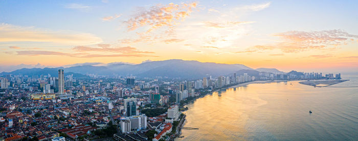 City by sea against sky during sunset