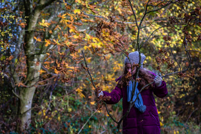 Girl holding bare twig in forest