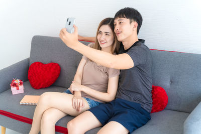 Young woman using mobile phone while sitting on sofa