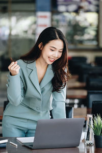 Young businesswoman using laptop while standing in cafe