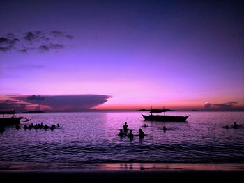 Silhouette people on beach against sky during sunset