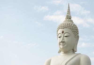 White buddha statue on sky background.