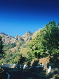 Cars on mountain against clear blue sky