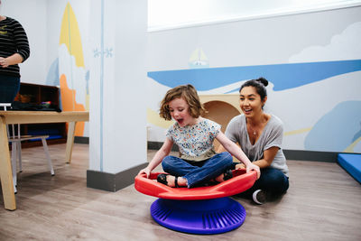 Teacher smiles while she spins her student on a sensory seat