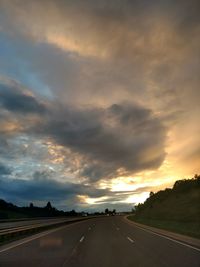 Cars on road against dramatic sky during sunset