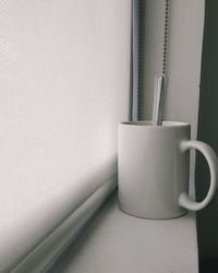 Close-up of coffee cup on table against wall