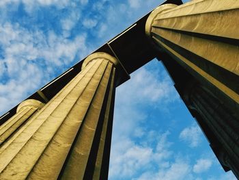 Low angle view of pillars against cloudy sky