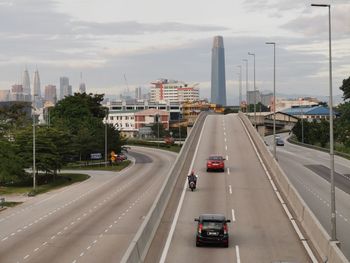 Vehicles on highway in city against sky