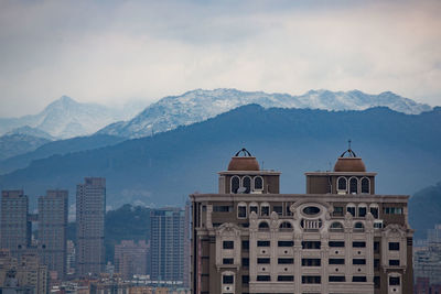 Buildings in city against cloudy sky