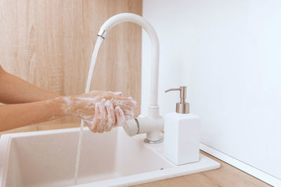 Cropped hand washing hands in bathroom