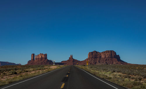 Road by mountain against clear blue sky