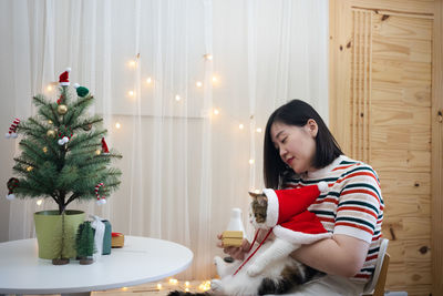 Side view of boy playing with christmas tree at home