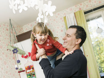 Father playing with daughter at home
