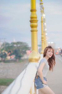 Side view portrait of happy woman standing on bridge at temple