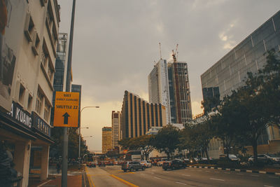 Road by buildings against sky in city