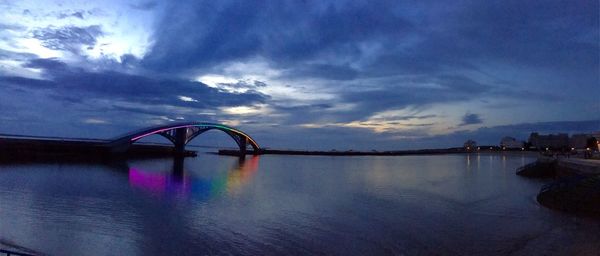 Silhouette bridge over sea against sky during sunset