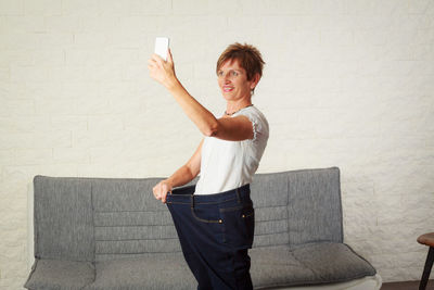 Full length of woman photographing on sofa