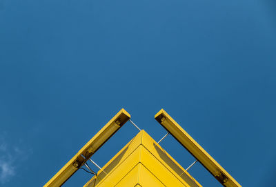 Low angle view of road sign against clear blue sky