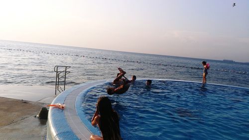 People enjoying at swimming pool by sea