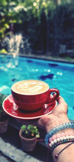 Close-up of hand holding coffee cup in swimming pool
