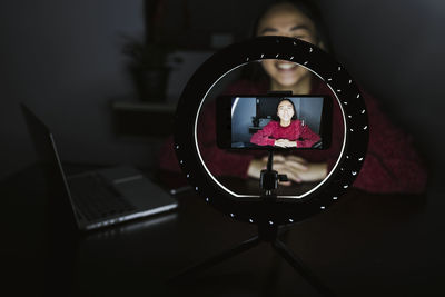 Smiling young female vlogger in darkroom