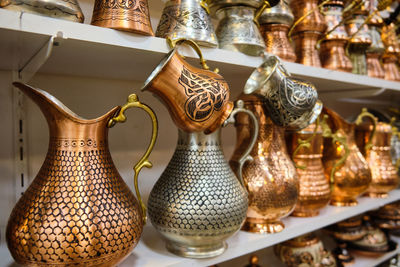 Lots of copper handmade jugs and cezves at shelf of a traditional middle-eastern souvenir store