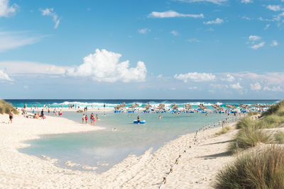 People enjoying at beach against sky on sunny day