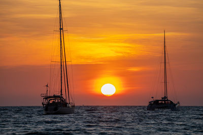 Sailboat sailing on sea against sky during sunset