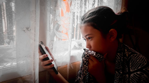 Portrait of woman holding mobile phone at home