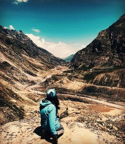 Woman looking at mountain while kneeling on ground