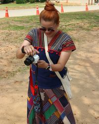 Smiling woman holding camera standing outdoors