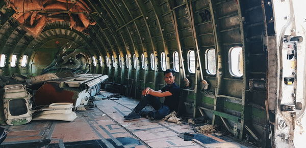 Full length of young man sitting in abandoned airplane