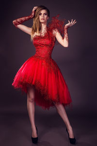 Beautiful young woman in fashion red dress posing in studio