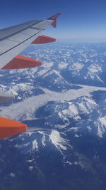 Aerial view of airplane wing over snowcapped mountains