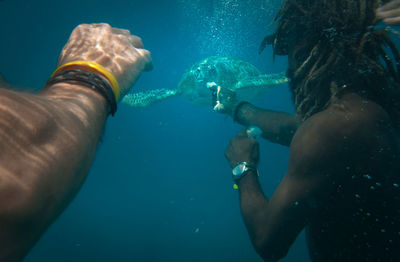 Men feeding turtle while snorkeling undersea