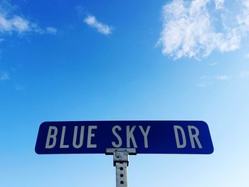 Low angle view of road sign against blue sky