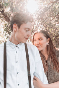 Young couple standing against tree