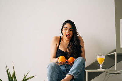 Young woman sitting on table against clear sky