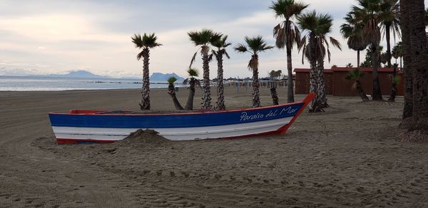 Boats moored on beach against sky