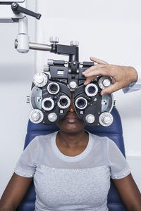 Optometrist adjusting the optometry equipment during study of the eyesight of a black woman